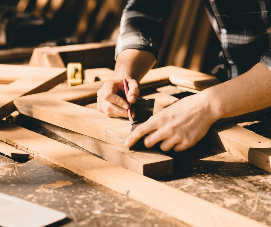 Carpenter marking a wood piece for precise cutting in birdhouse construction